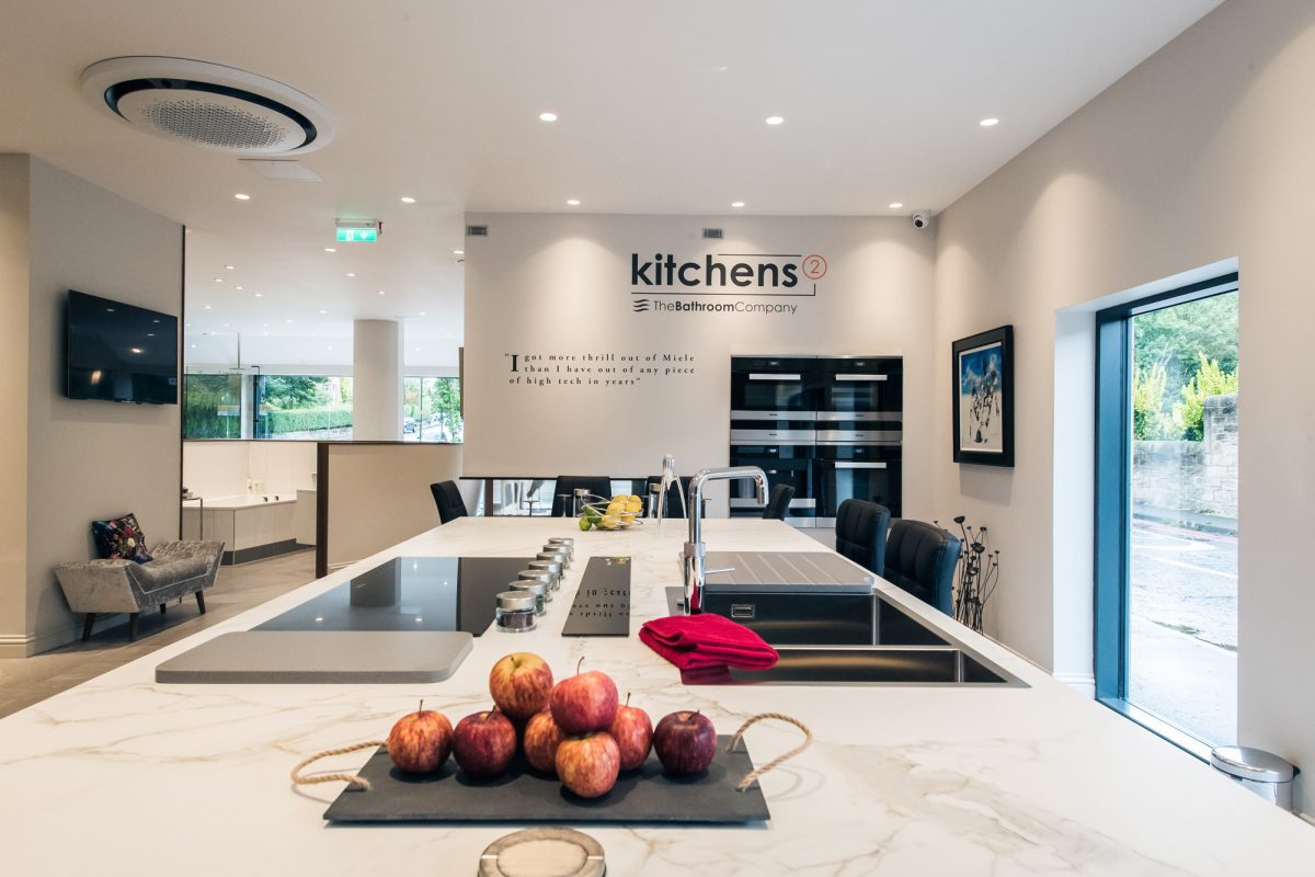 A large kitchen island on display at the Kitchens2 studios in Edinburgh. On top of the island is a sink, a Quooker tap and a Dekton worktop.