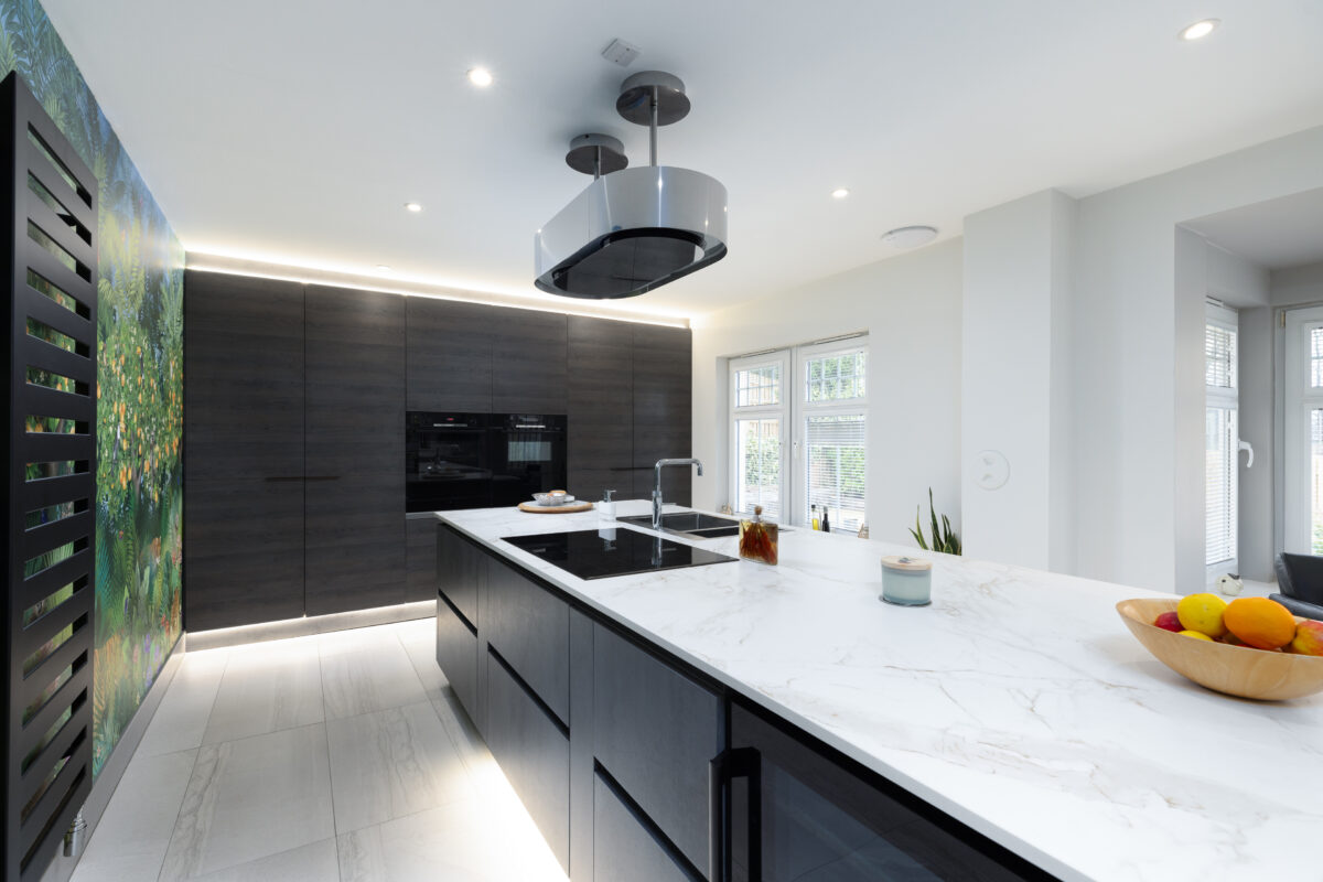 A modern kitchen renovation with floral wallpaper and a large fitted cabinet with integrated appliances.