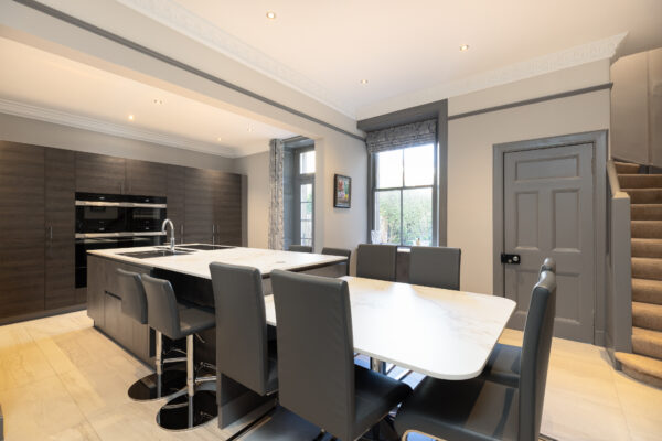 Bespoke kitchen renovation with fitted cabinetry and integrated appliances. The kitchen space also features a kitchen island and a dining area.