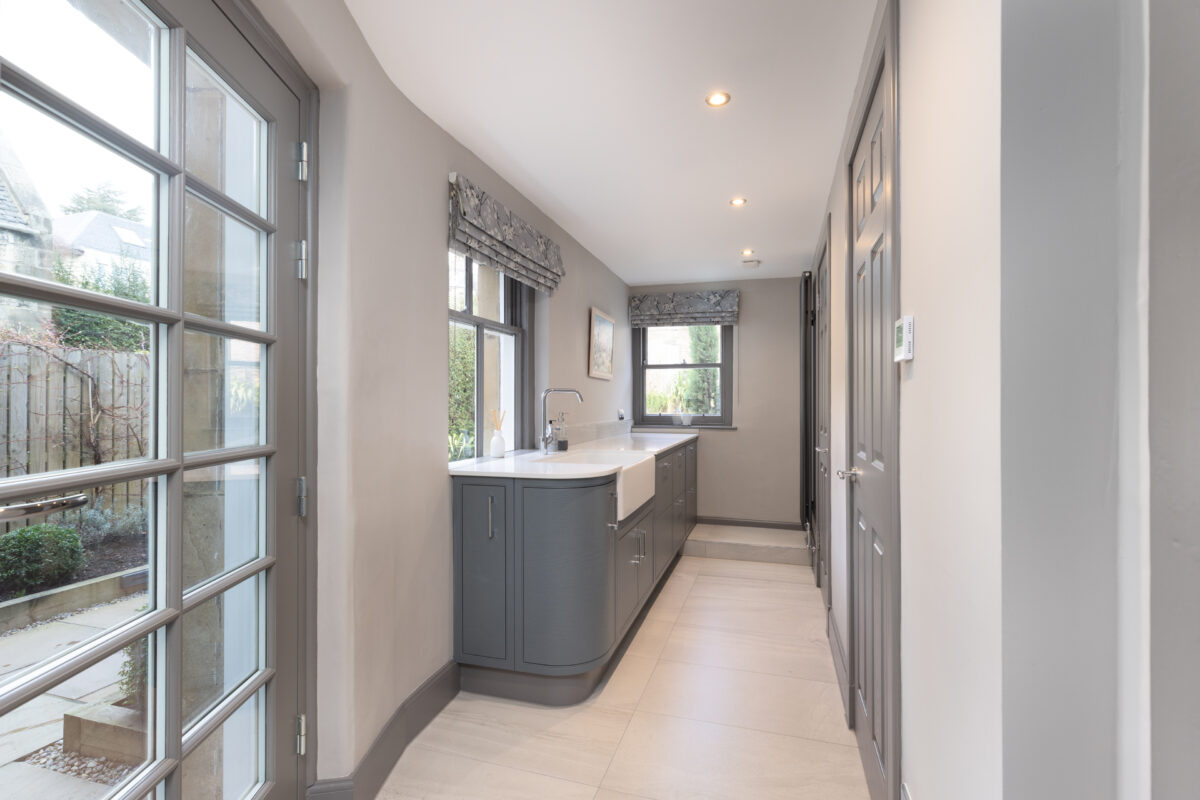 Utility room renovation featuring a separate laundry and boiler room. The space includes a farmhouse-style sink complemented by ample storage cabinets.