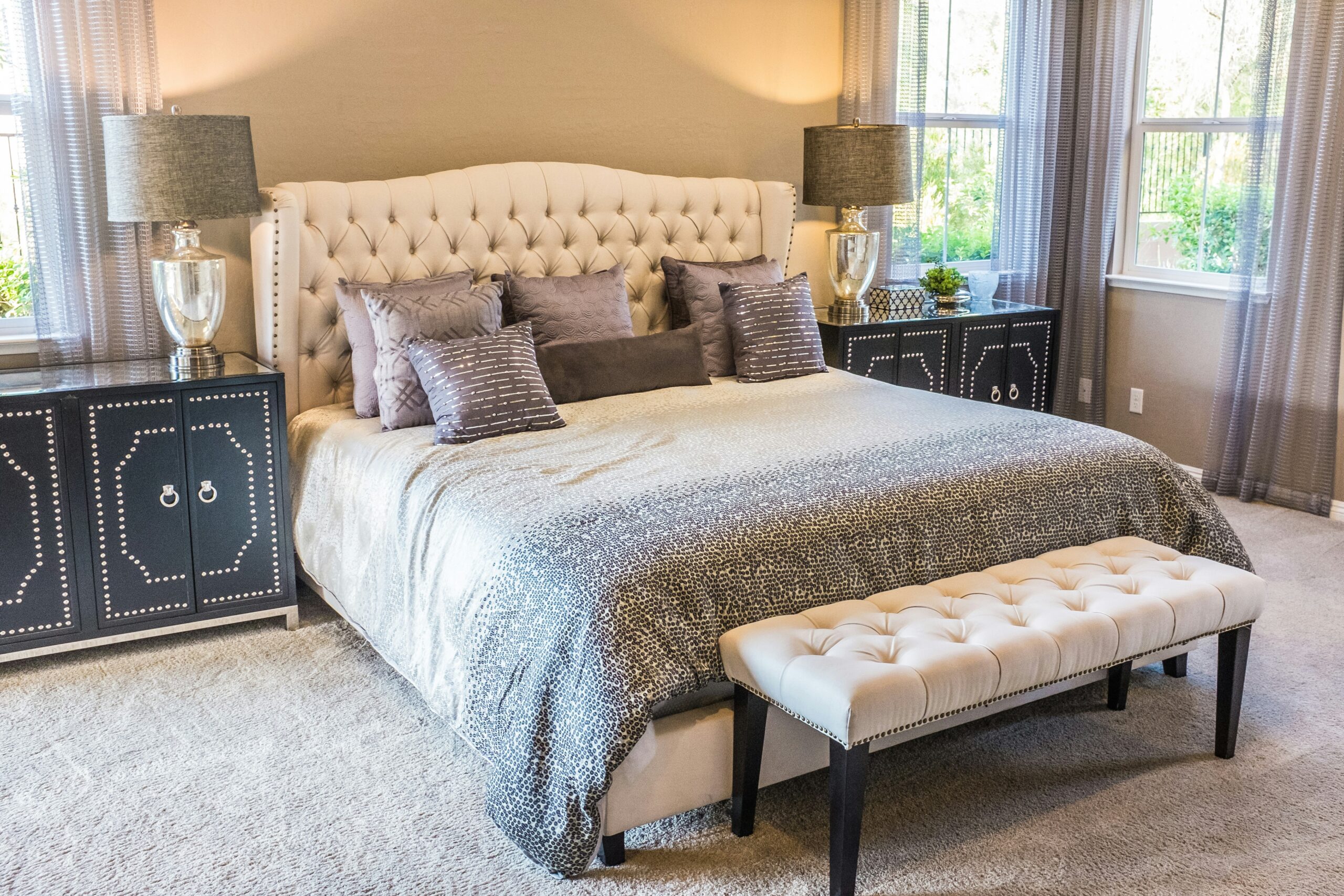 A traditional style bedroom with a large bed with beside two beside lamps on top of each storage unit.