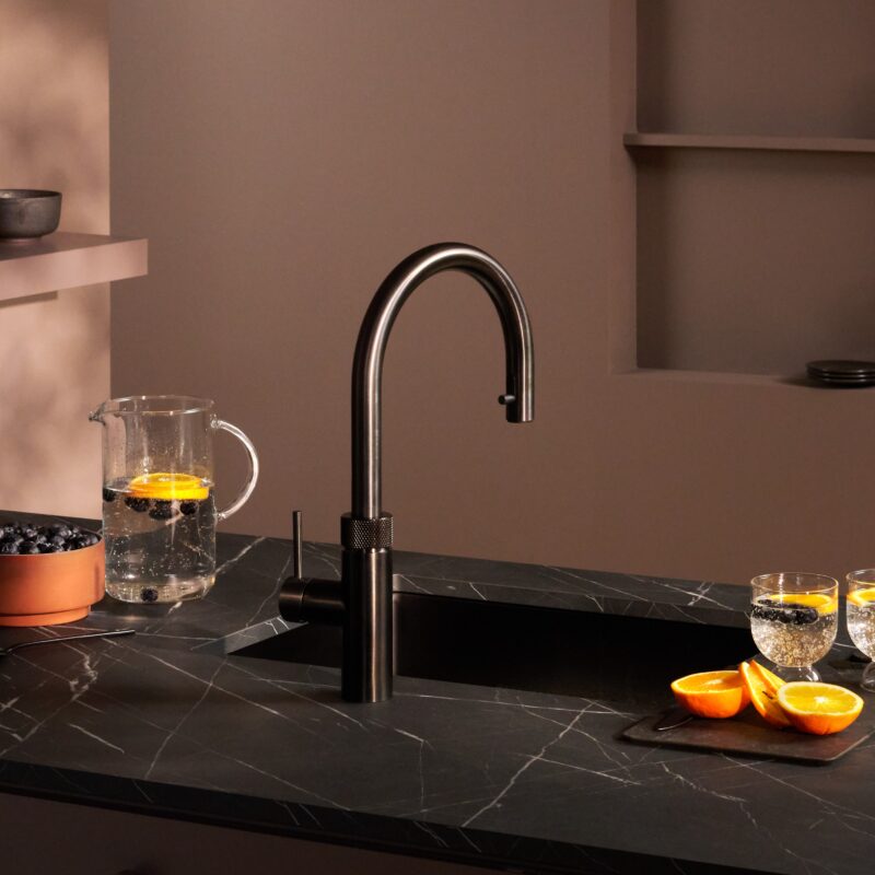 A stylish kitchen island featuring a stone countertop and a Quooker tap for instant boiling water.