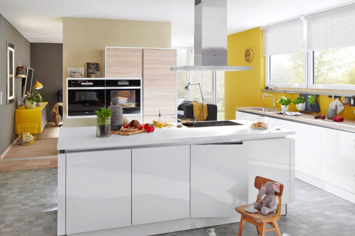 A bright kitchen with yellow and white walls, a clean white countertop with sink, and a tap from Hansgrohe.