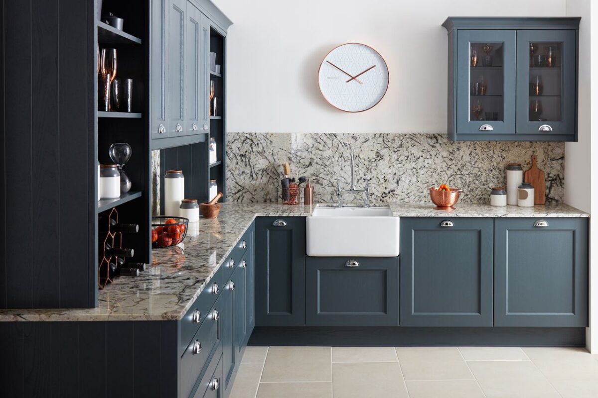 A modern kitchen with blue bespoke cabinets from Burbige and a sleek counter top.