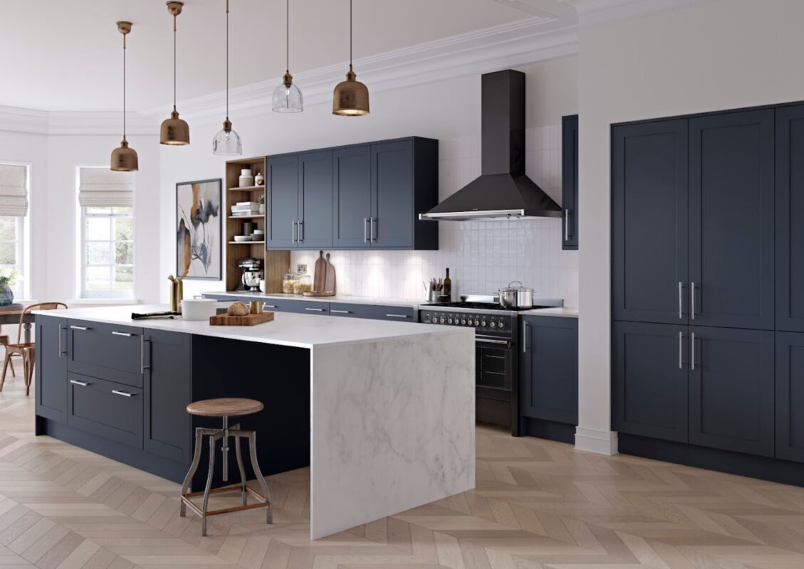 A modern kitchen renovation featuring wall, base, and recessed tall units in a dark blue finish, complemented by white stone worktops for an elegant colour scheme.