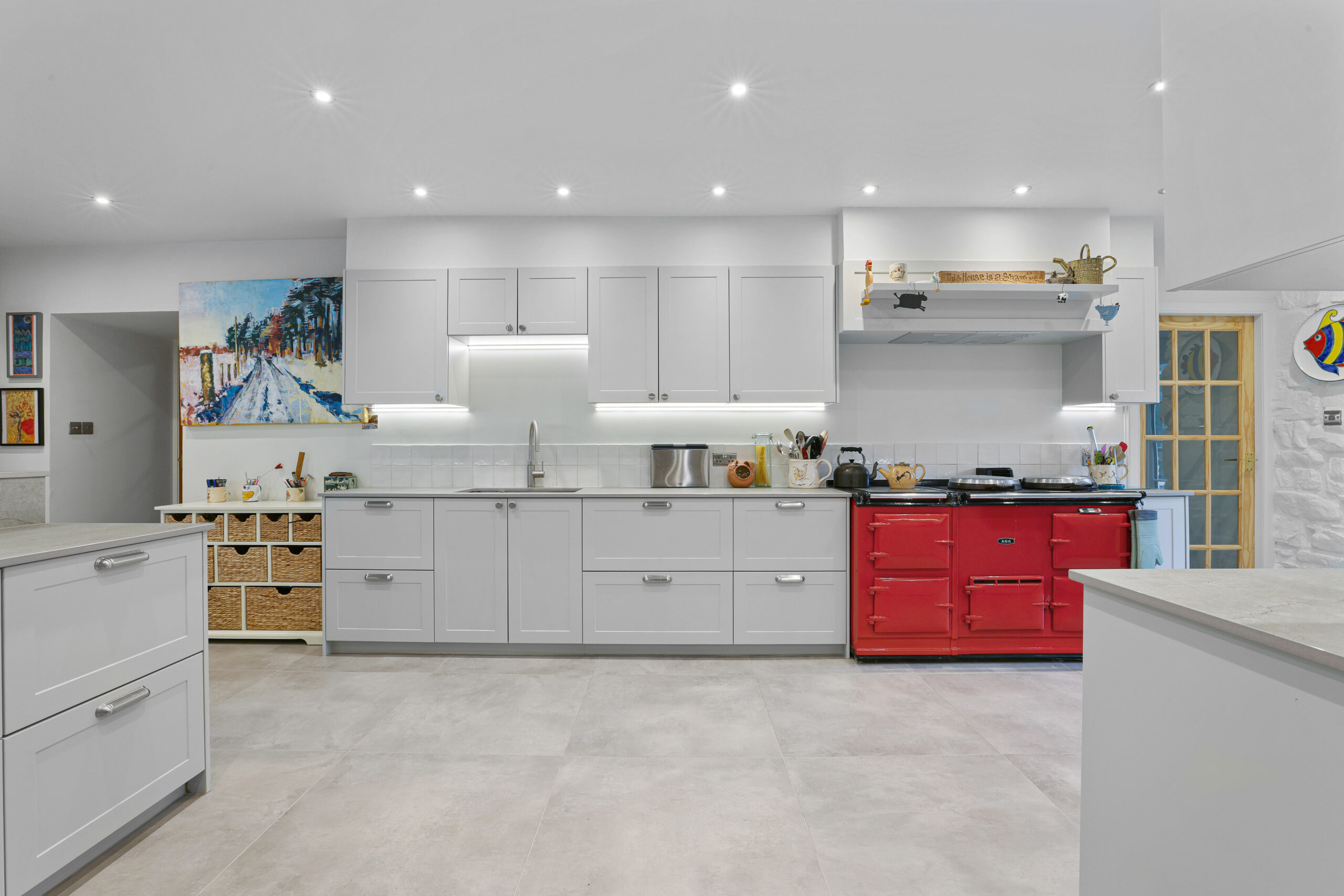 An elegant kitchen renovation with a spacious, open layout, featuring a cast-iron cooker that adds character to the white colour scheme.